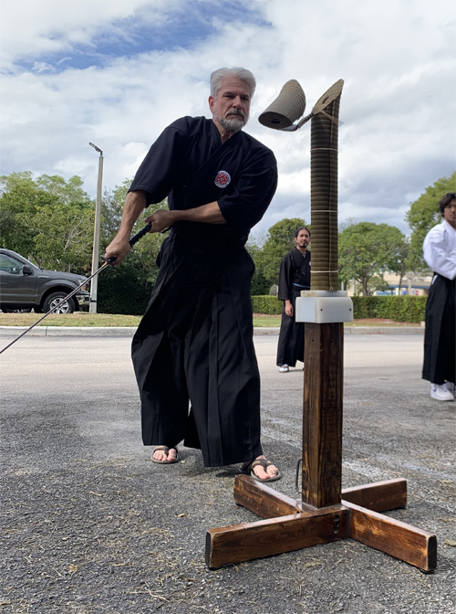 Adult batto - a man cutting thru a mat with a real sword blade